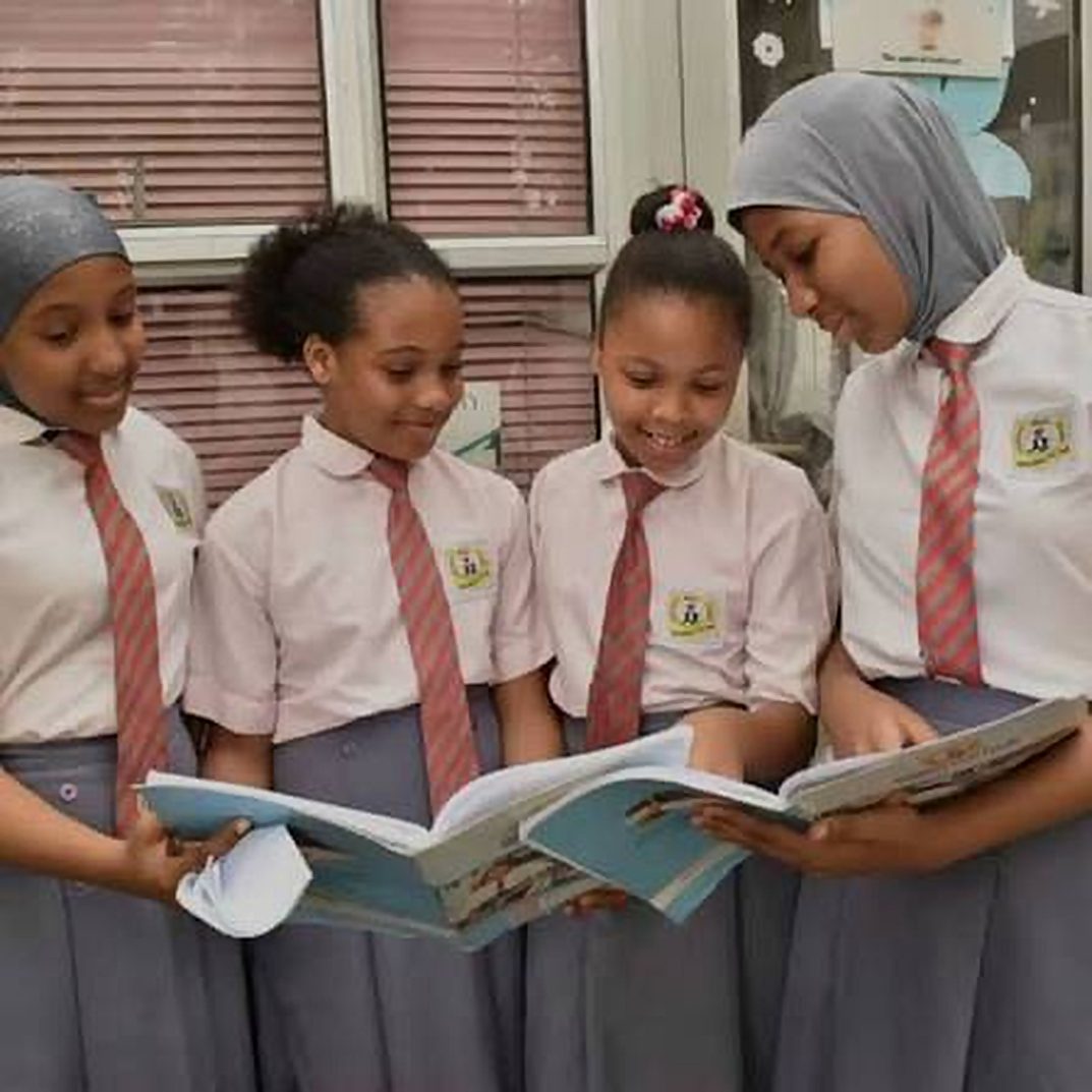 Four Knightdale Middle College students in uniform reading a book together