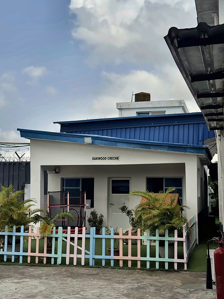 Oakwood Creche, a white building with a blue roof, palms and a pastel fence