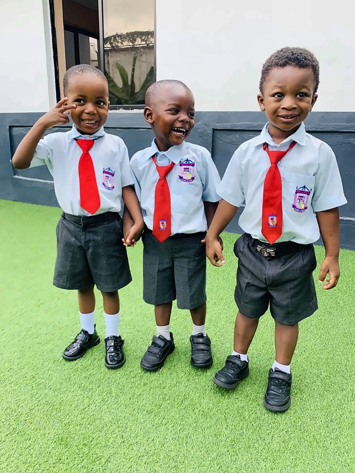 Three Priscilla School pupils laughing together in their uniforms: light blue shirts with the school crest, red ties and grey shorts