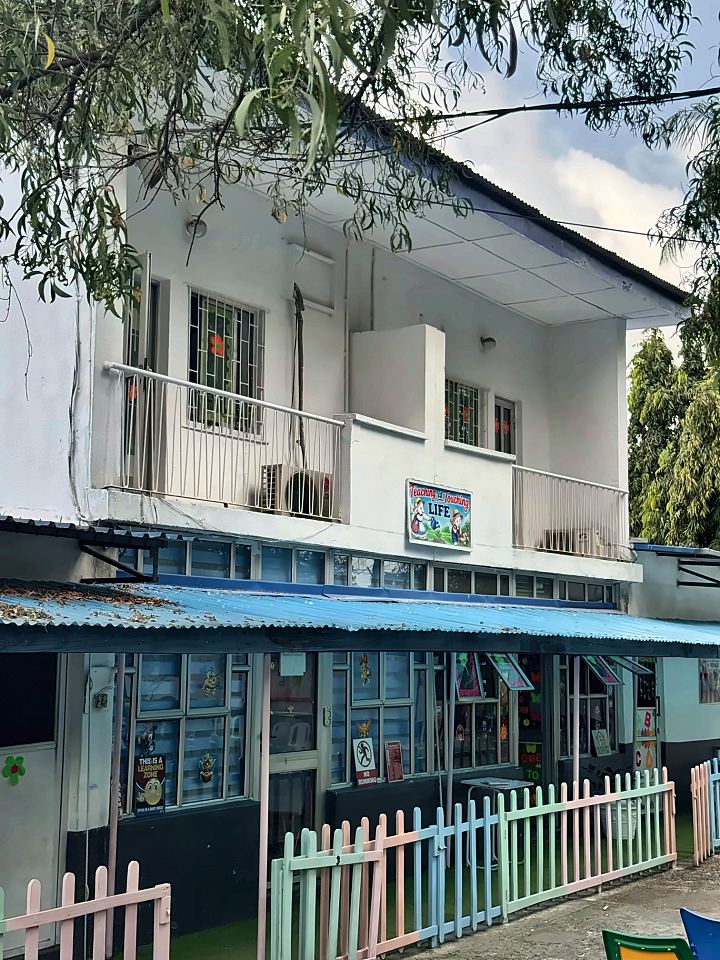 Two-storey classroom block with a sign reading Teaching is Touching Life